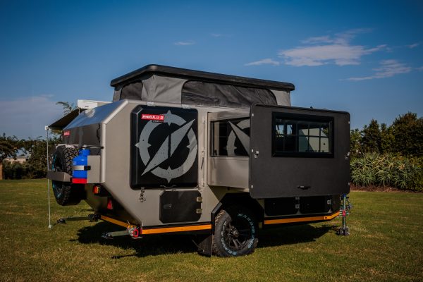 This photo shows an Infanta 4x4 Enkulu 2 caravan on grass in front of a blue sky